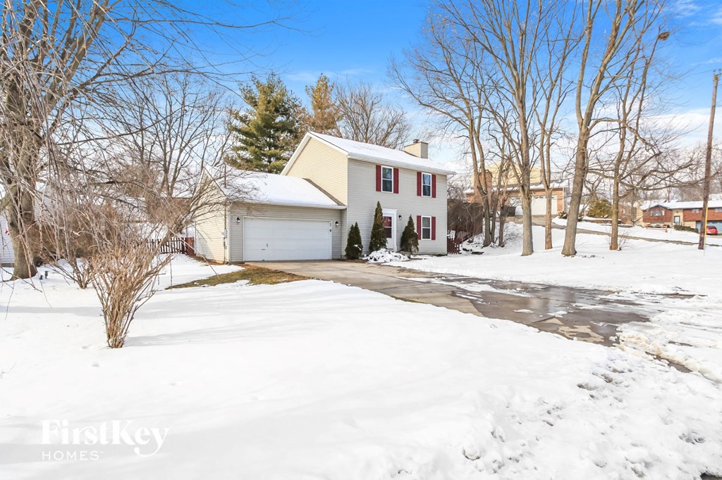 a white house with a driveway in the snow