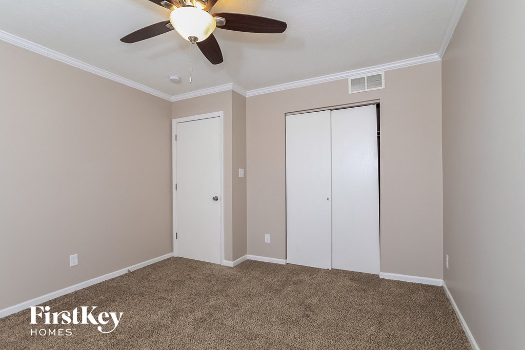 a bedroom with a ceiling fan and two closet doors