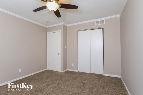 a bedroom with a ceiling fan and two closet doors