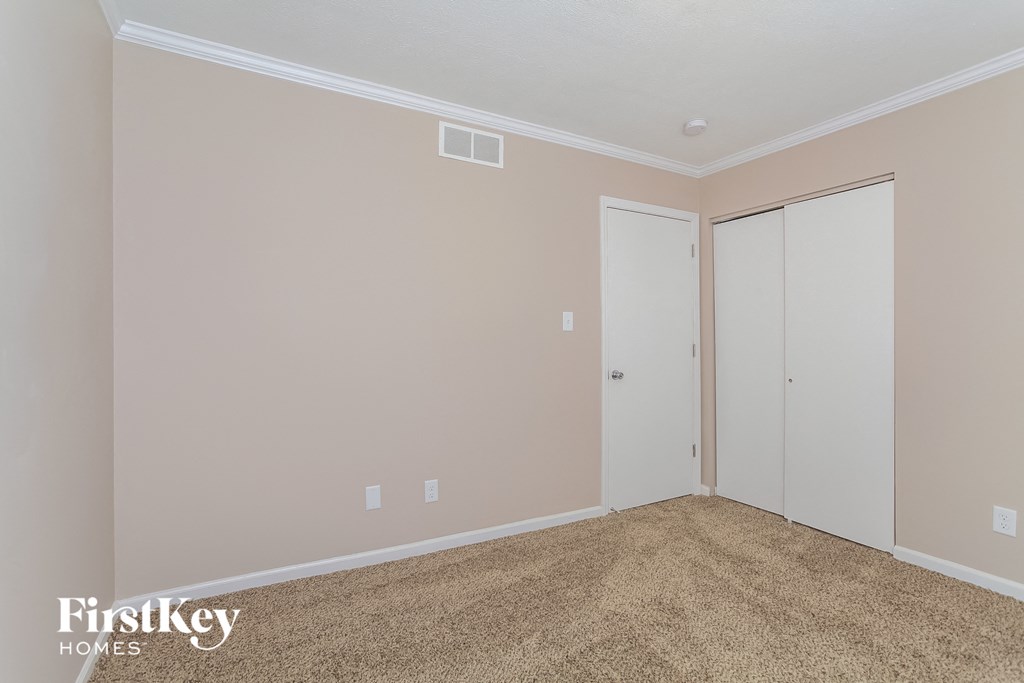 a bedroom with a carpeted floor and two closet doors