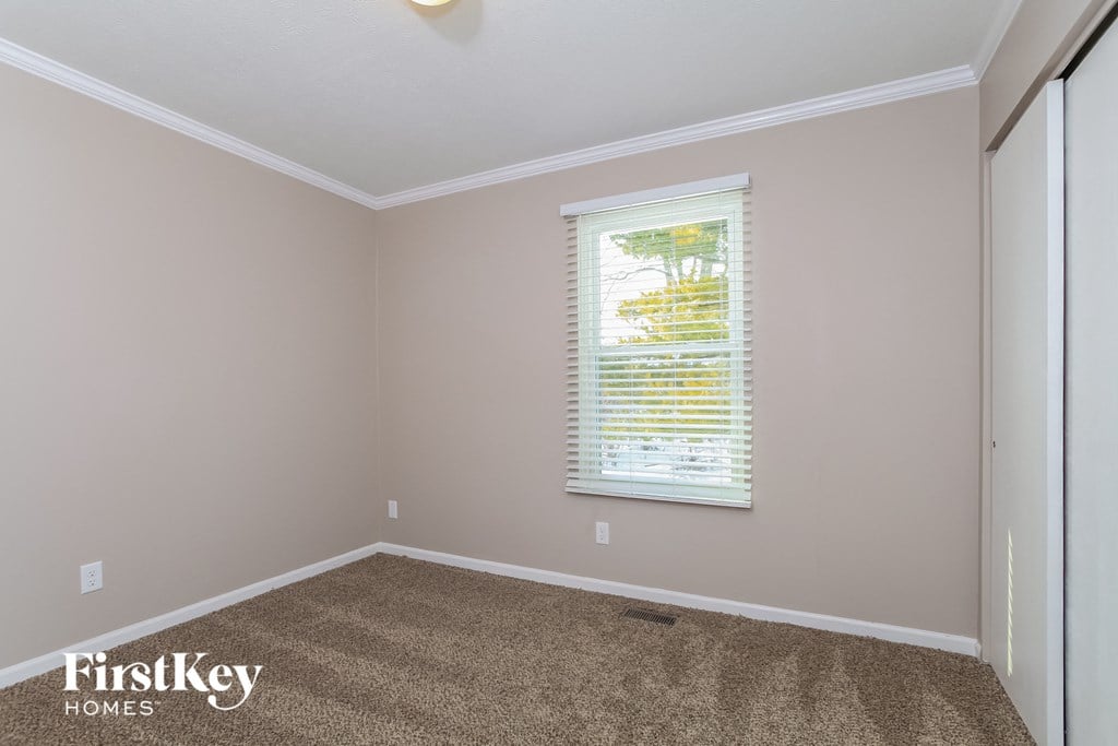 a room with a carpeted floor and a window with blinds