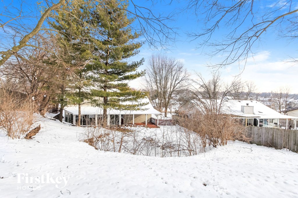 a house covered in snow next to a tree
