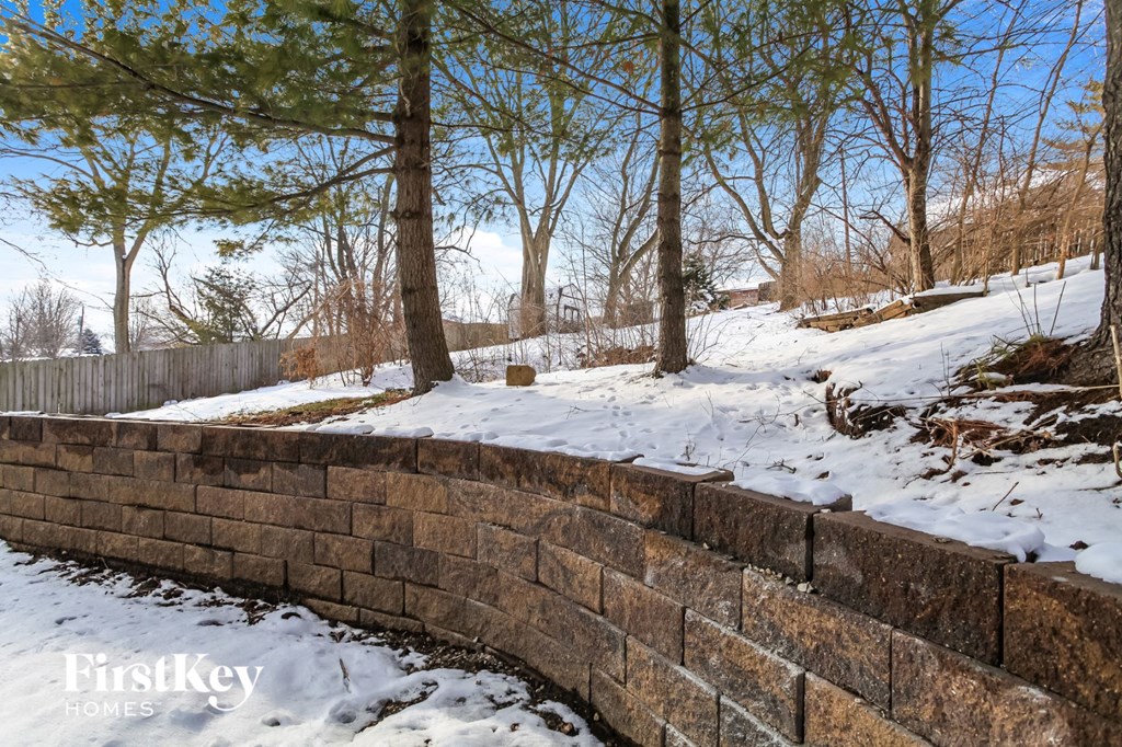 a stone retaining wall surrounds a stream in the snow