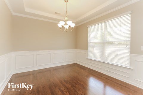 a dining room with wood floors and a window and a chandelier