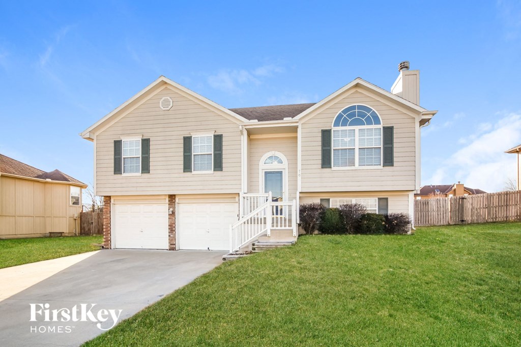 a beige house with a white garage door and a lawn