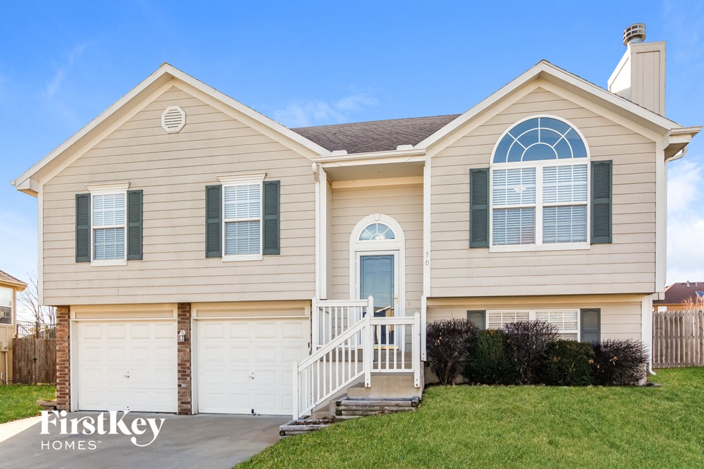 a tan house with green shutters and a front porch