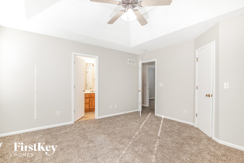 a master bedroom with carpet and a ceiling fan