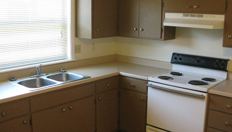 A kitchen with a white stove and brown cabinets.