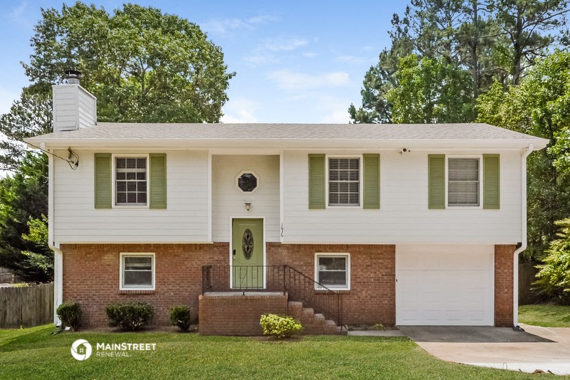 a white house with green shutters and a green door
