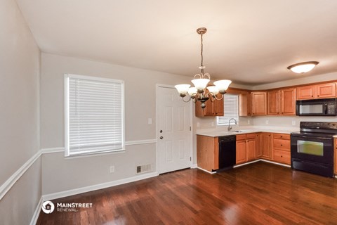 the kitchen and dining room of a house with wood flooring and wooden cabinets