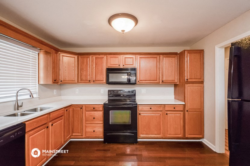 an empty kitchen with wooden cabinets and black appliances
