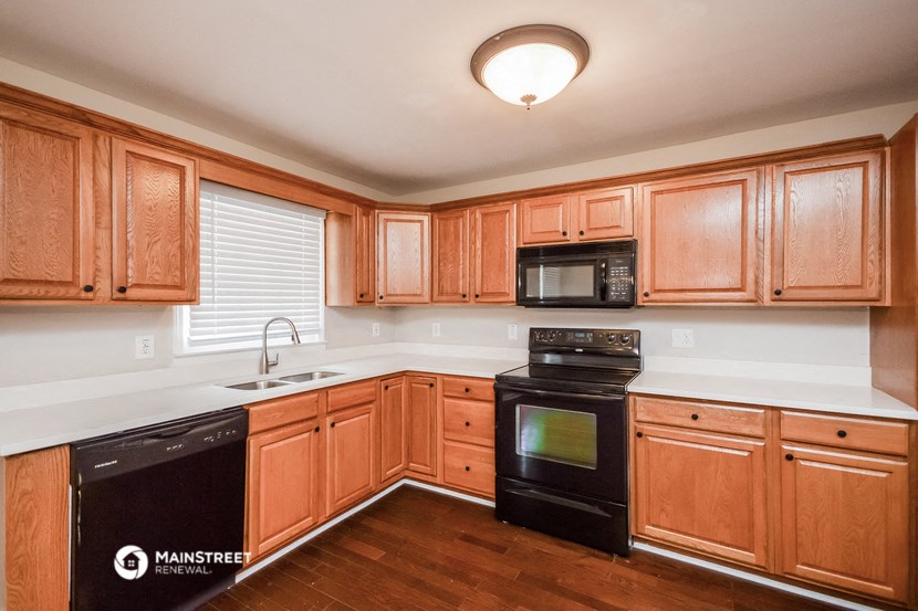 an empty kitchen with wooden cabinets and black appliances