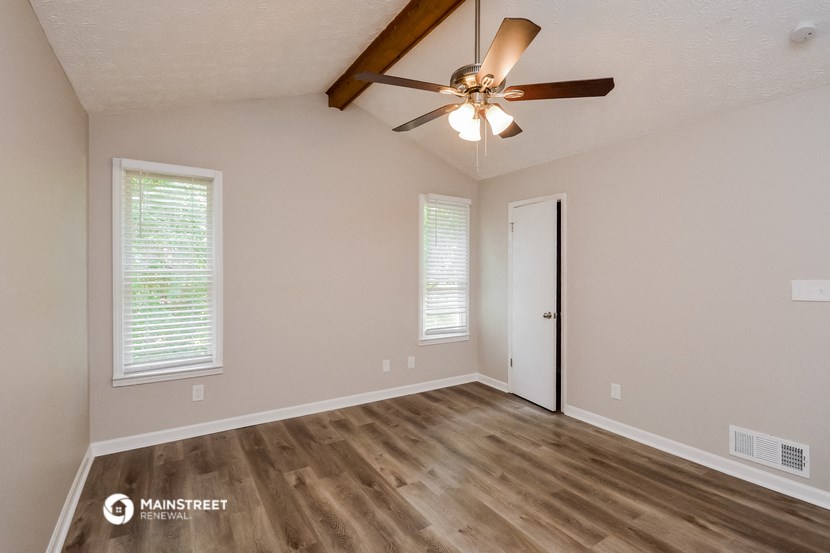 the spacious living room with ceiling fan and wood flooring