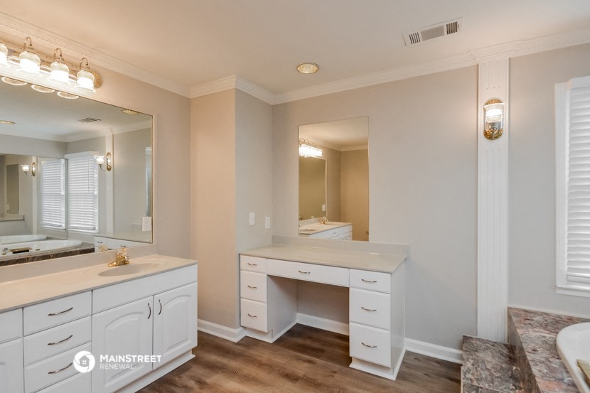 a bathroom with white cabinets and a large mirror