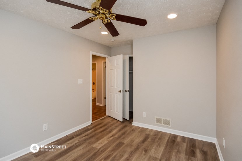 a living room with a ceiling fan and a door to a hallway
