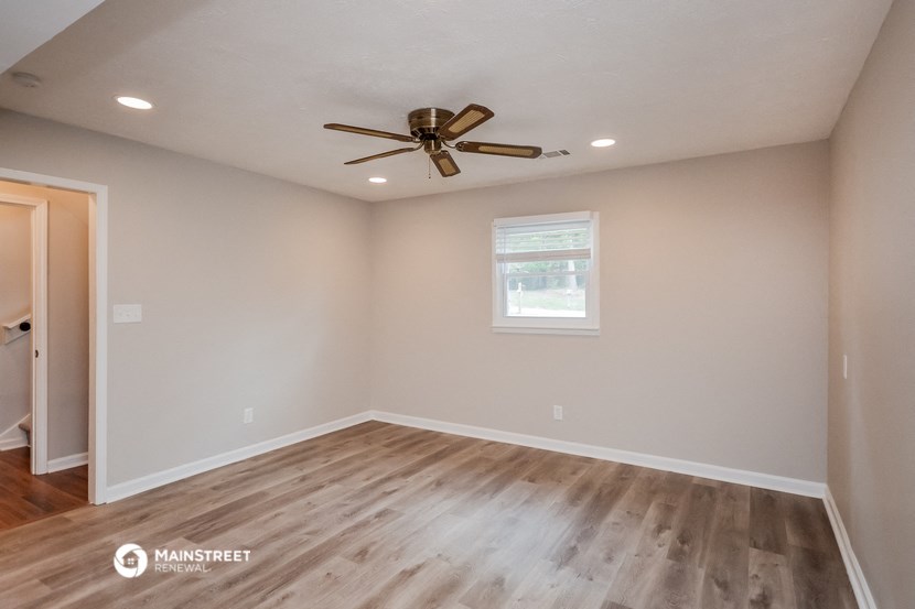 the spacious living room with hardwood floors and a ceiling fan