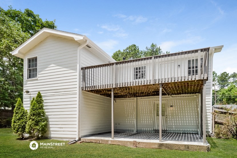 a white house with a deck on top of a garage
