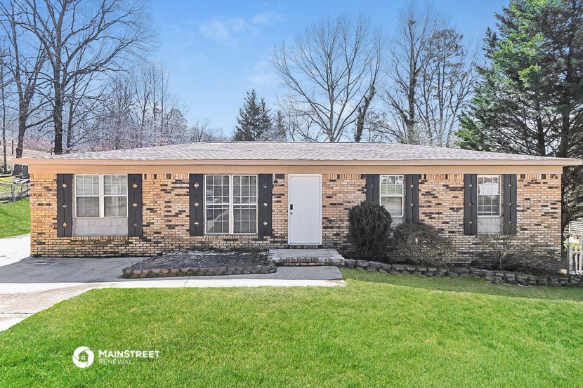 a small brick house with black shutters and a lawn