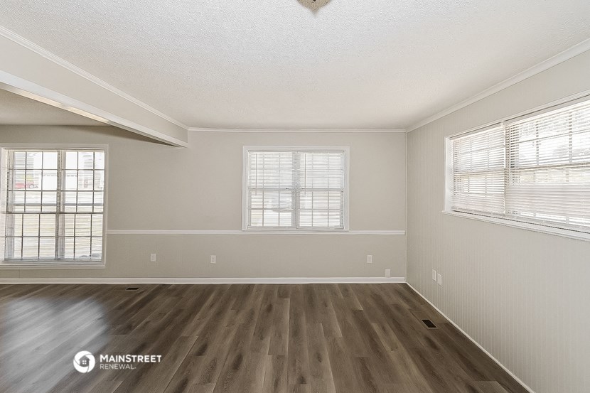 the spacious living room with hardwood flooring and two windows