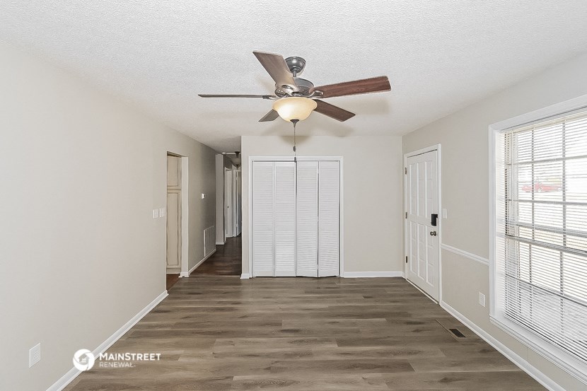 a living room with a ceiling fan and a hallway
