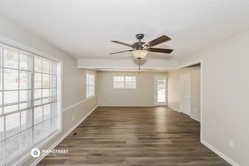 an empty living room with a ceiling fan and a large window