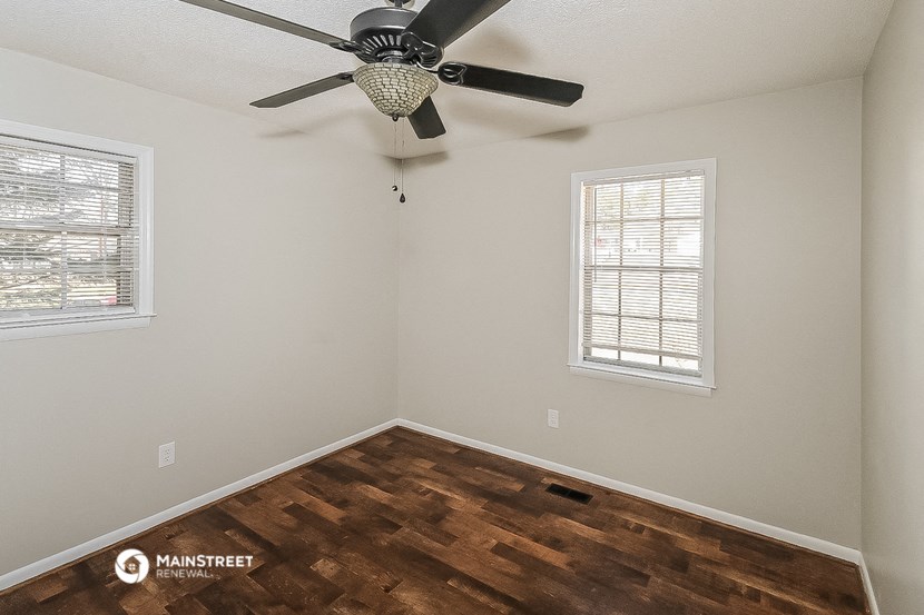 the bedroom has a ceiling fan and wood flooring