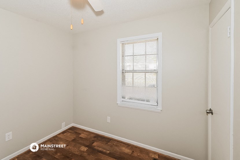 a bedroom with a wood floor and a window