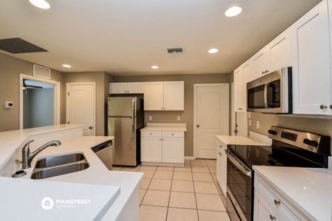 a kitchen with white cabinets and a sink and a refrigerator