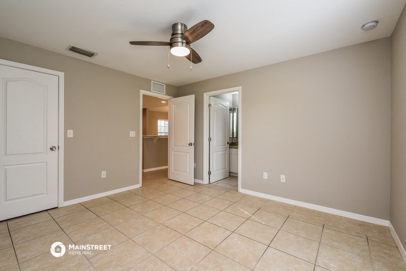 the living room is spacious with tile flooring and a ceiling fan
