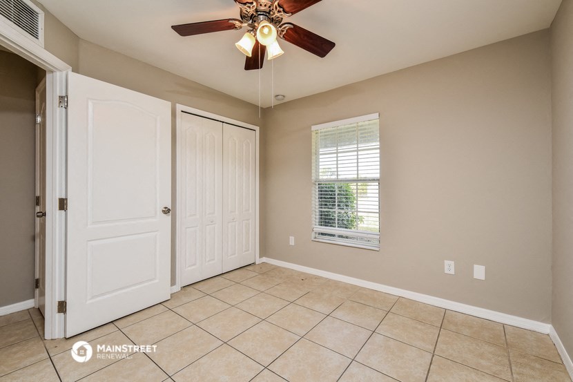 an empty living room with a ceiling fan and a door to a closet