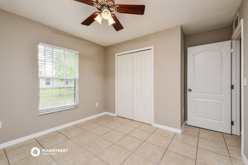 an empty living room with a ceiling fan and a door