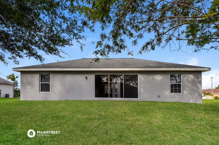 a white house in a grassy yard with a tree