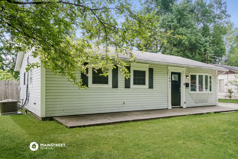 a white house with a porch and a tree