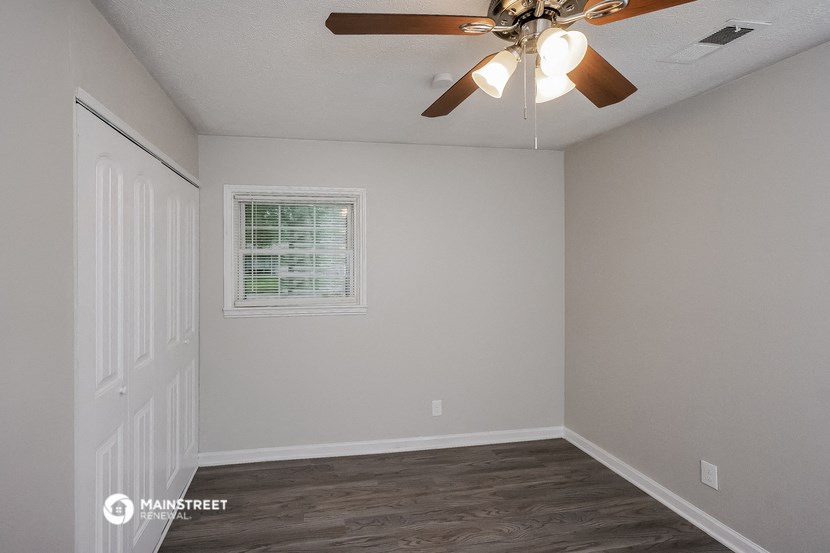 the bedroom of a house with a ceiling fan