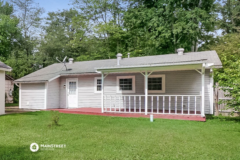 a small white house with a porch on a lawn