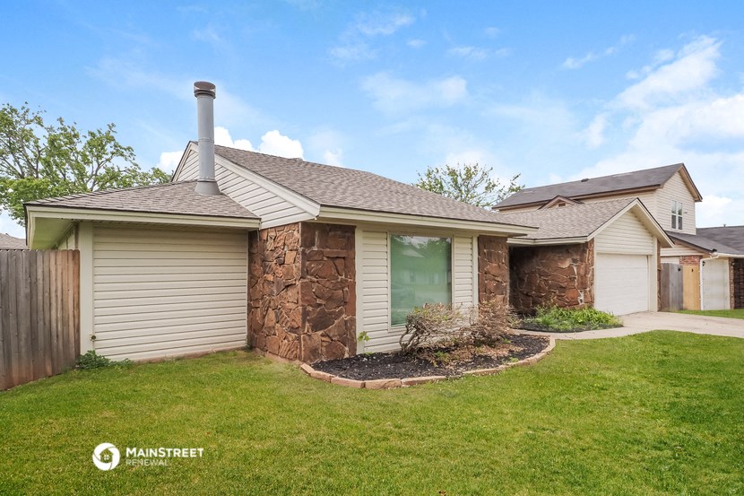 a home with a stone facade and a green lawn