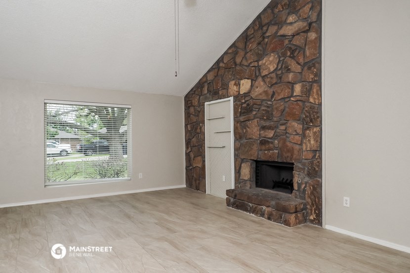 the living room has a large stone fireplace and a large window
