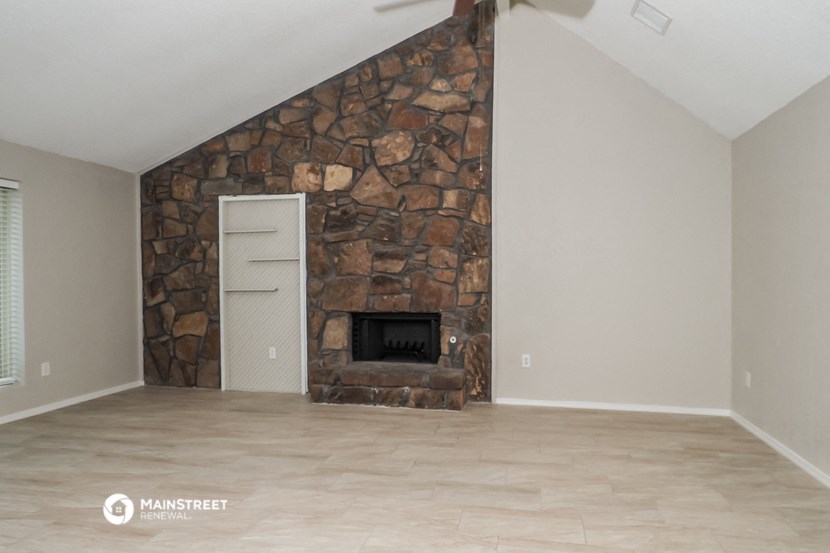 an empty living room with a fireplace and a stone wall