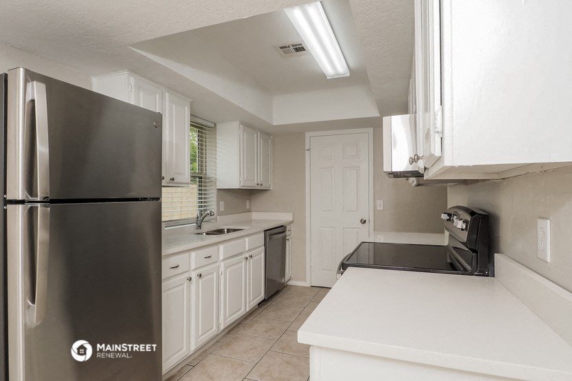 a kitchen with white cabinets and a stainless steel refrigerator