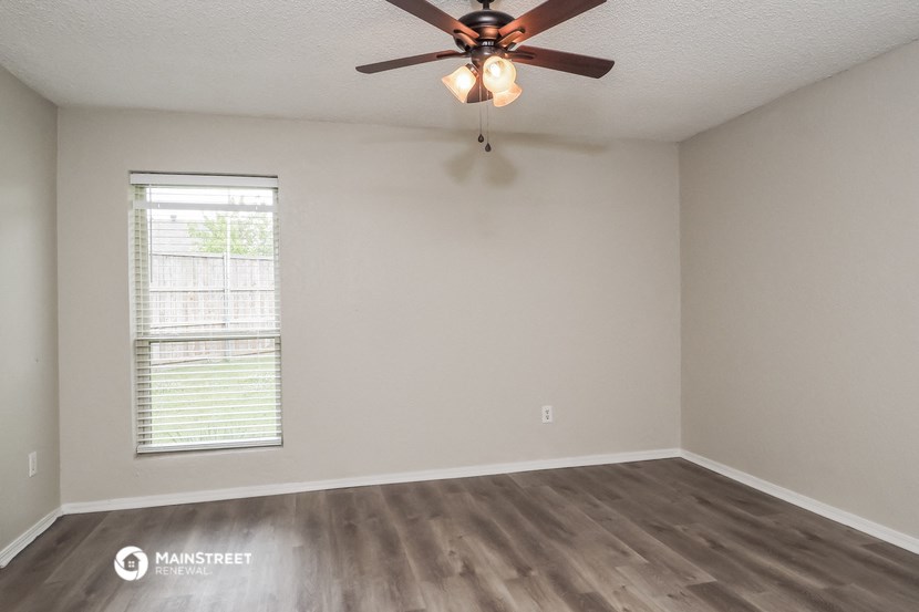 an empty living room with a ceiling fan and a window