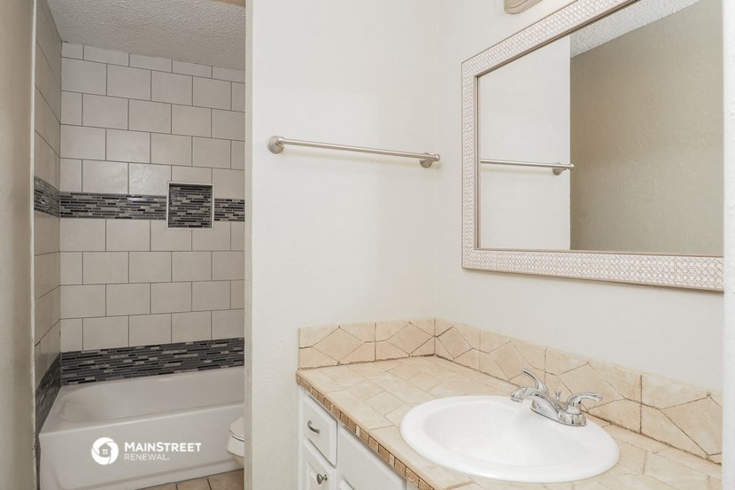a bathroom with a sink and a shower and a mirror