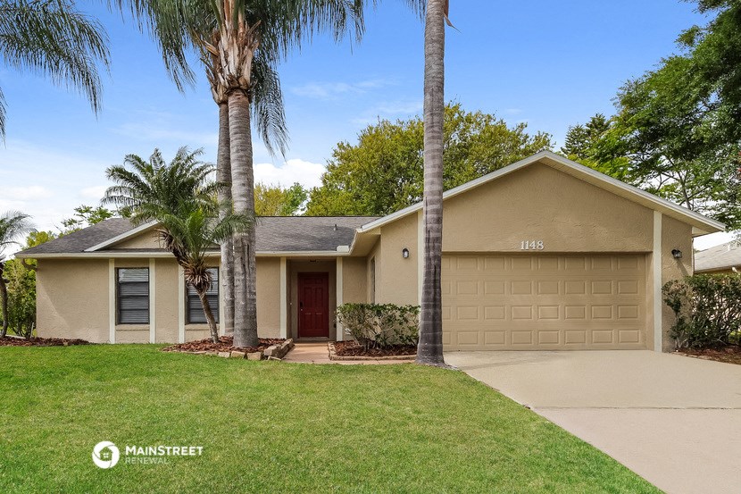 a tan house with palm trees and a driveway