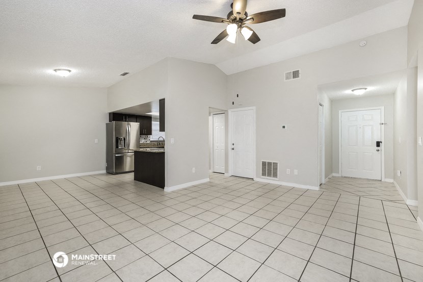 an empty living room with a ceiling fan and a tiled floor