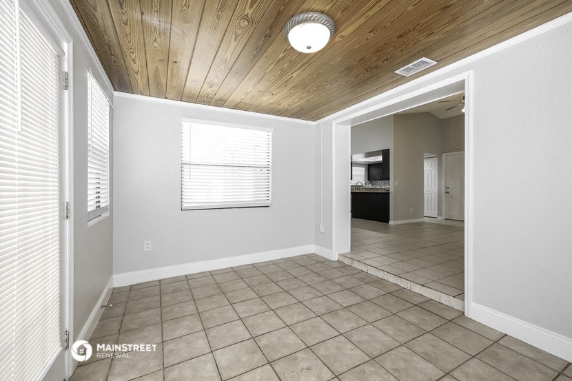 an empty living room with a tile floor and a wood ceiling