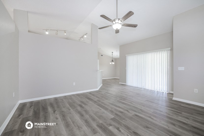 an empty living room with a ceiling fan and a window