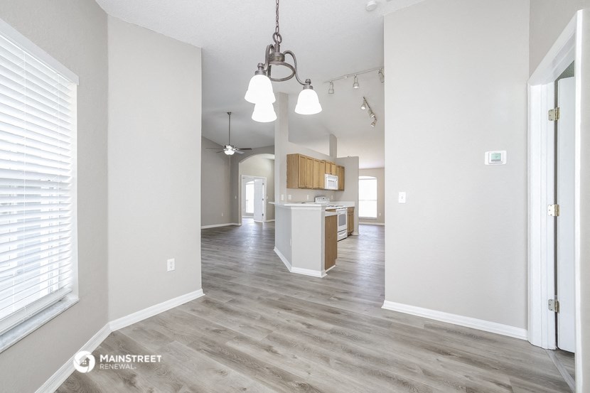 an open kitchen and living room with white walls and wood flooring