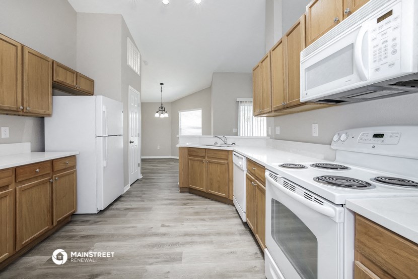 an empty kitchen with white appliances and wooden cabinets