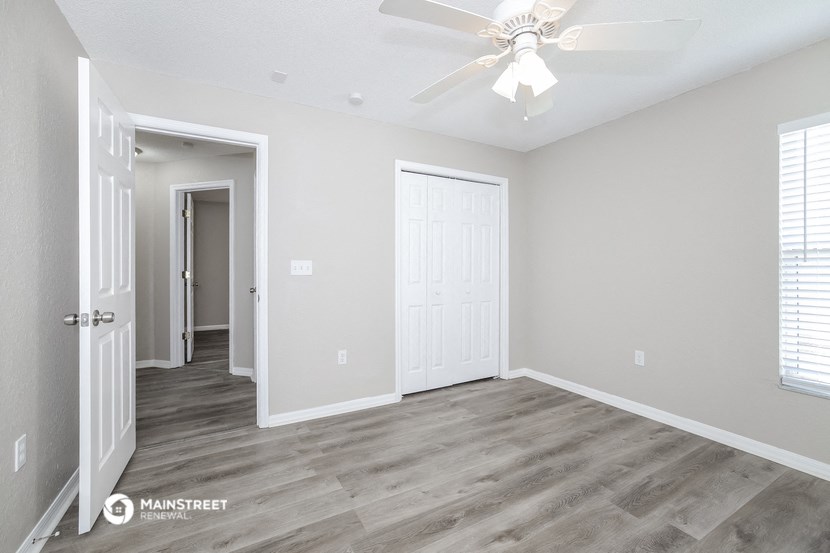 the living room of a new home with white walls and a ceiling fan