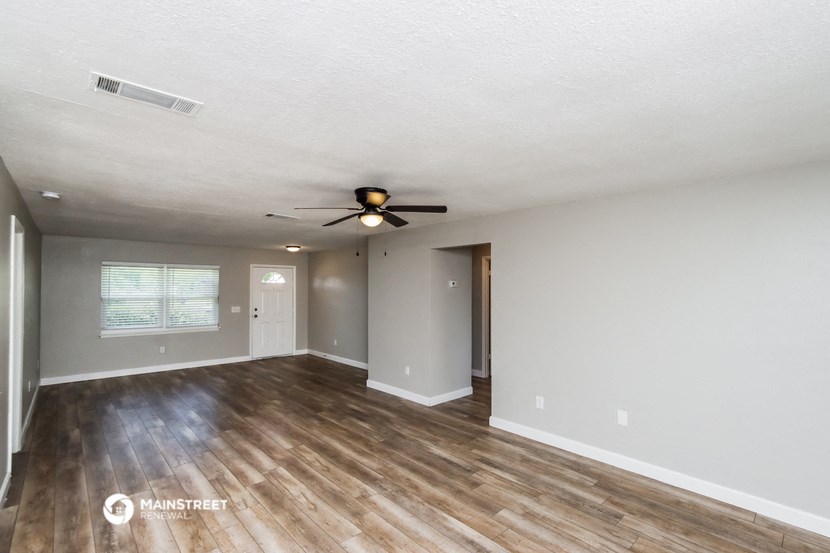 the living room of an empty house with a ceiling fan