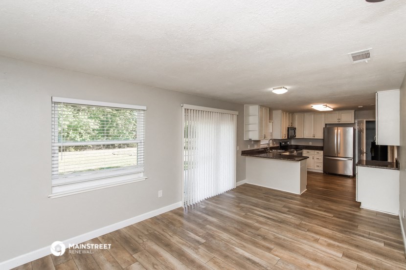 the spacious living room and kitchen of an apartment
